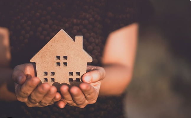 small wooden house held up by hands